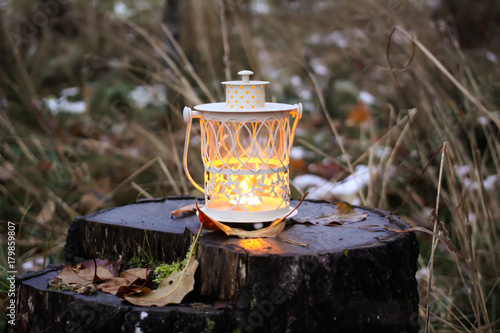 Decorative lantern with burning candle in autumn park at evening.