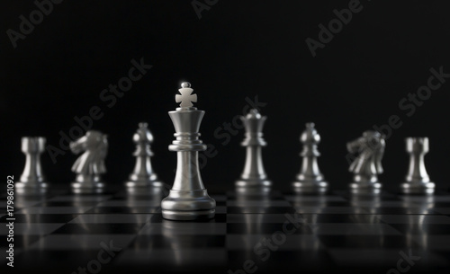 Chess (King in front of chess figures in row) on black background. Leader, leadership, business strategy, success, victory, win, winner, intellect, checkmate, brave, fearless or undaunted concept.