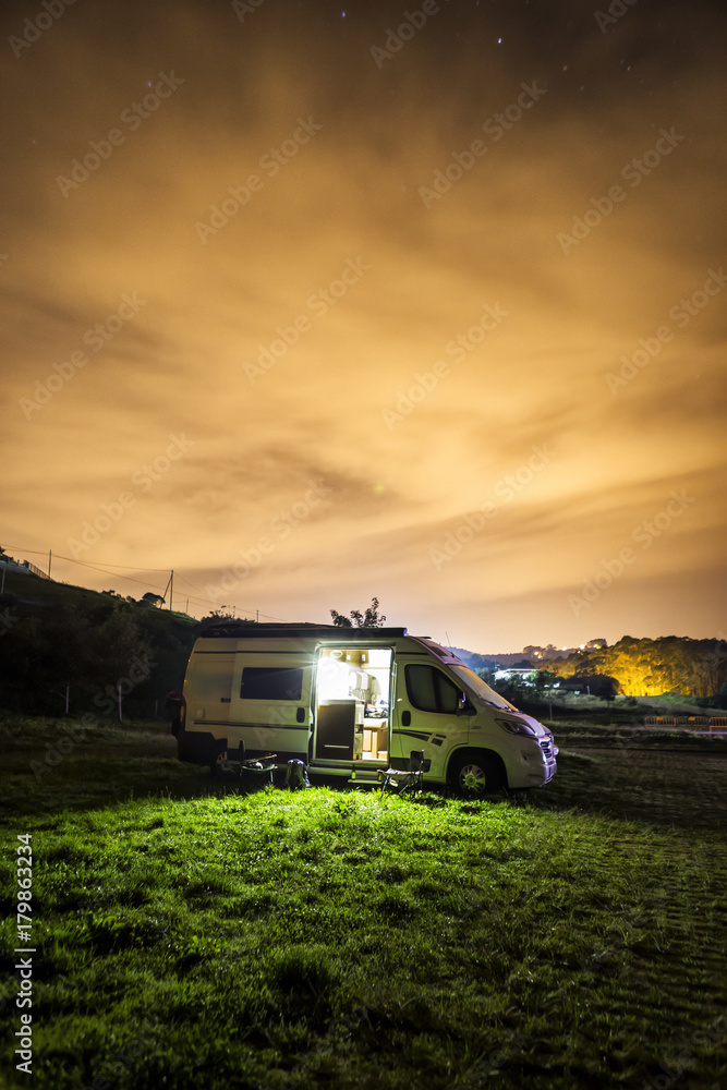 Fotografía nocturna de una autocaravana aparcada sobre un prado