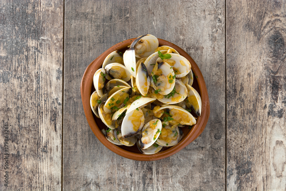 Clams with marinera sauce.Almejas a la marinera. Spanish recipe on wooden table.Top view Clams with marinera sauce.Almejas a la marinera. Spanish recipe on wooden table.Top view