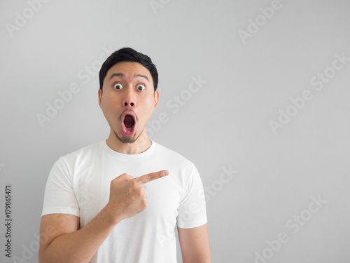 Shocked face of man in white shirt on grey background. photo