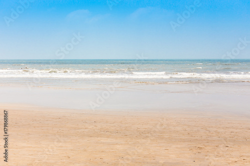 View from a tropical sandy beach on the turquise sea with clear water and sunny sky.