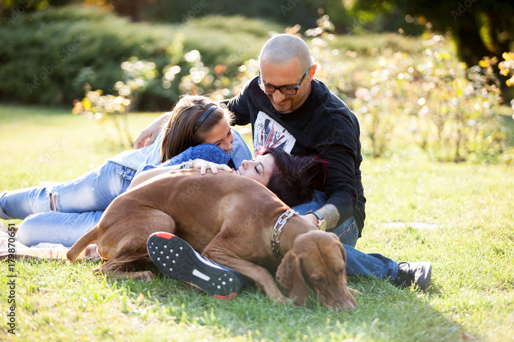 Playing with a dog in the park. Animal lovers. Mother, father, daughter and their dog Playing with a dog in the park. Animal lovers. Mother, father, daughter and their dog
