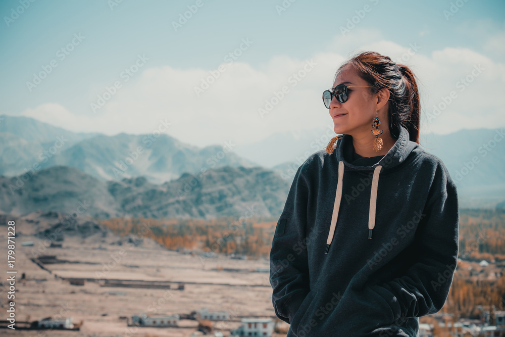 Portrait image of a beautiful Asian woman standing on the top of view point  with Leh city background