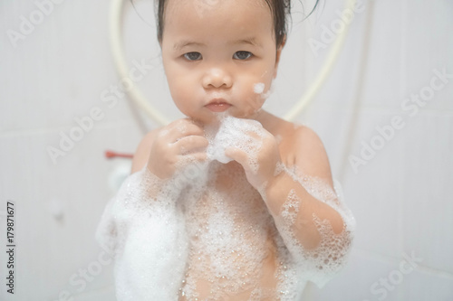 Wallpaper Mural Little asian girl taking shower in bathroom, playing bath foam bubbles. Selective focus Torontodigital.ca