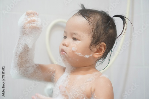 Wallpaper Mural Little asian girl taking shower in bathroom, playing bath foam bubbles. Selective focus Torontodigital.ca