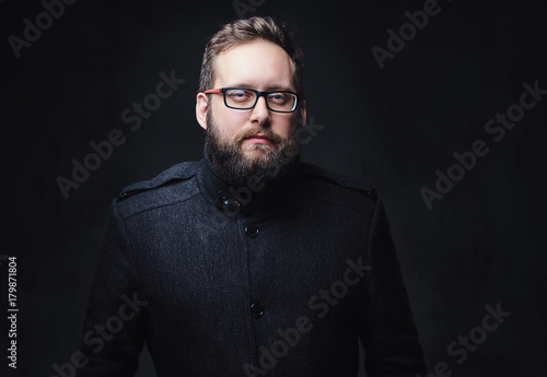 Serious plump male in eyeglasses over grey background.
