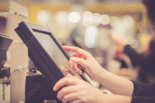 Young woman hands counting / entering discount / sale to a touchscreen cash register, market / shop (color toned image) photo