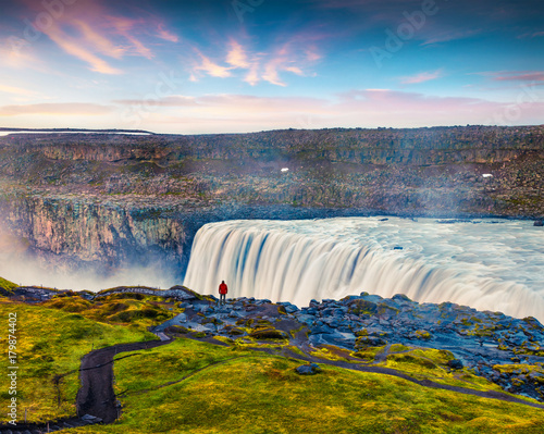 Tourist admiring view of falling water of the most powerful waterfall in Europe - Dettifoss