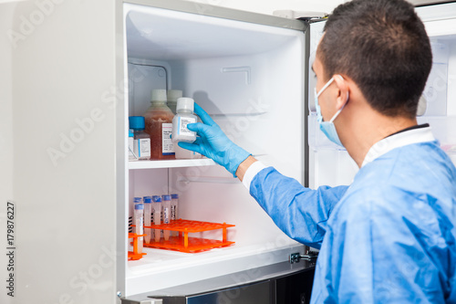 Young male scientist and laboratory freezer photo