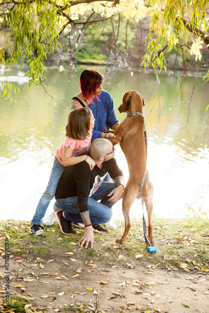 Happy family of father, mother and daughter on the riverside playing with their dog. Animal lovers Happy family of father, mother and daughter on the riverside playing with their dog. Animal lovers