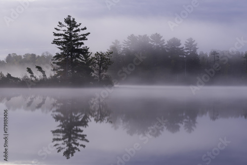 Early morning fog drifts silently across the surface of a secluded North Woods lake in northern Wisconsin.