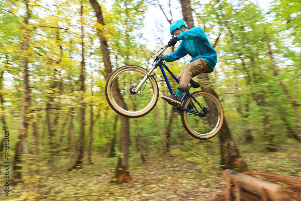 Naklejka premium a young guy in a helmet flies landed on a bicycle after jumping from a kicker