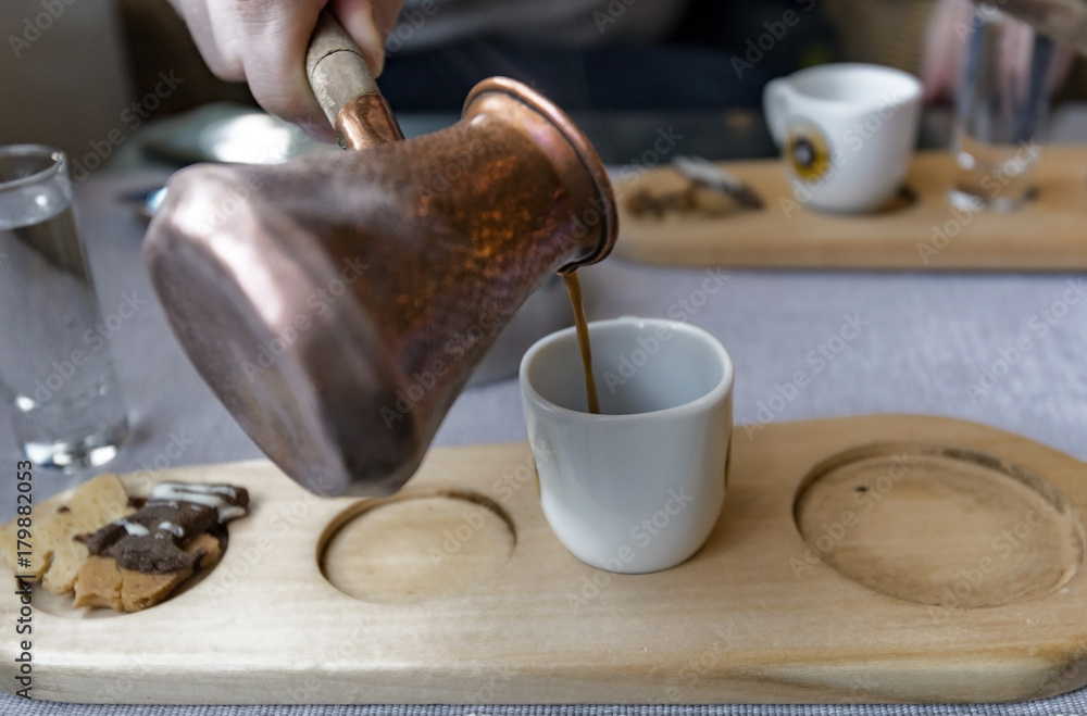 Man holding traditional Turkish pot and making Turkish coffee, metal coffee turk at a coffee shop Man holding traditional Turkish pot and making Turkish coffee, metal coffee turk at a coffee shop