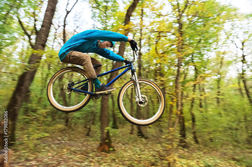 a young guy in a helmet flies landed on a bicycle after jumping from a kicker