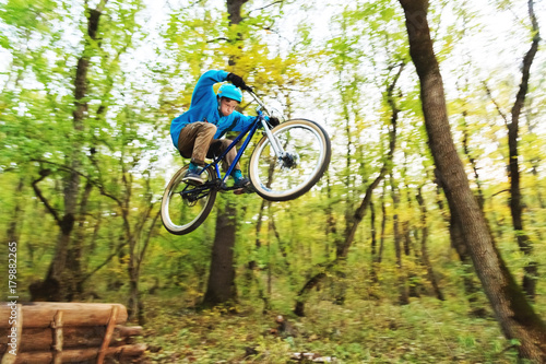 a young guy in a helmet flies landed on a bicycle after jumping from a kicker