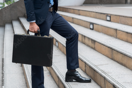 business success work concept : businessman hold professional briefcase walking upstairs
