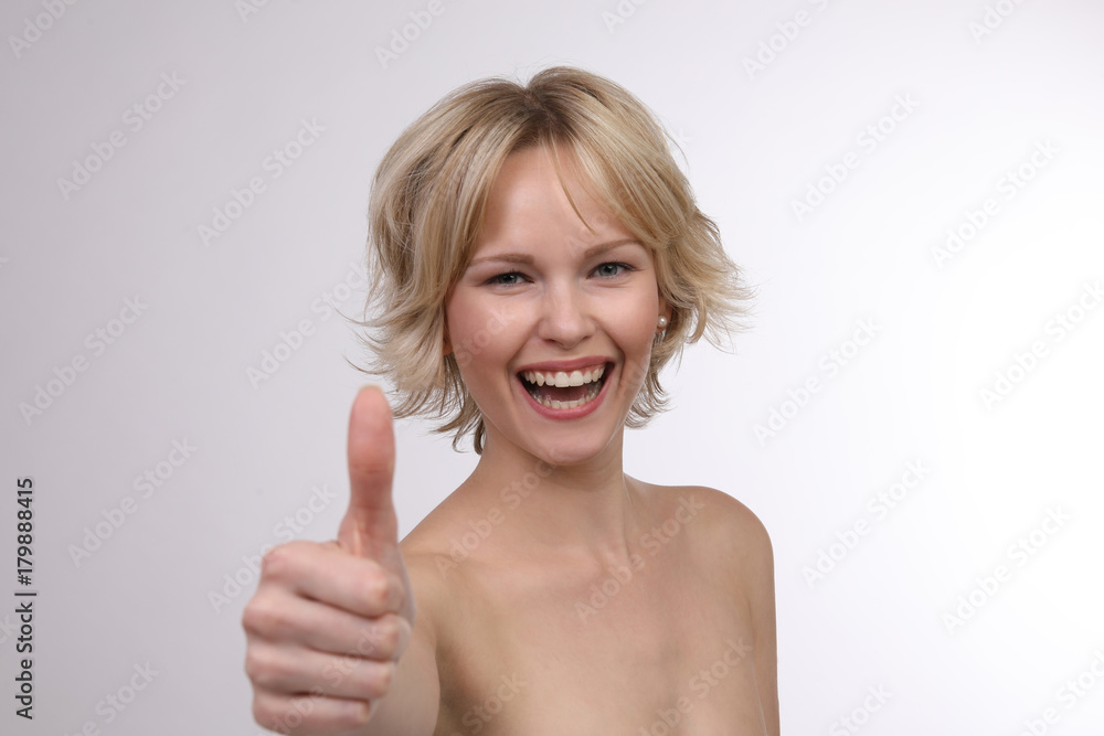 Hübsche blonde Frau mit nackten Schultern lacht und Daumen hoch Hübsche blonde Frau mit nackten Schultern lacht und Daumen hoch