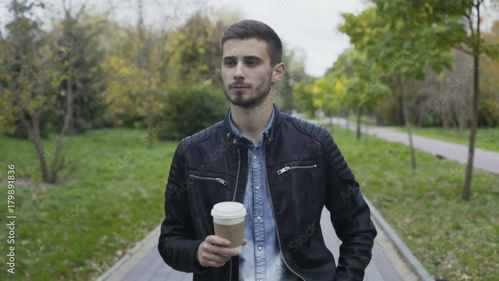 Handsome man walks on autumn park alley and drinks coffee 4K Handsome man walks on autumn park alley and drinks coffee 4K