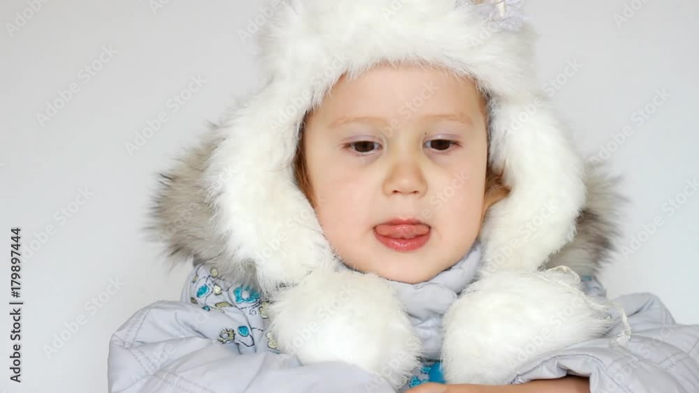 A funny happy child dressed in warm fur clothes looks at the camera, laughs and smiles. Close-up portrait. The concept of winter, frost and snow, cold weather, Cool temperature and Christmas A funny happy child dressed in warm fur clothes looks at the camera, laughs and smiles. Close-up portrait. The concept of winter, frost and snow, cold weather, Cool temperature and Christmas
