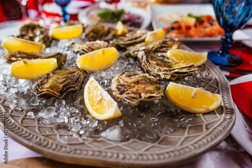 Oysters with lemon and ice on the plate on the dinner table