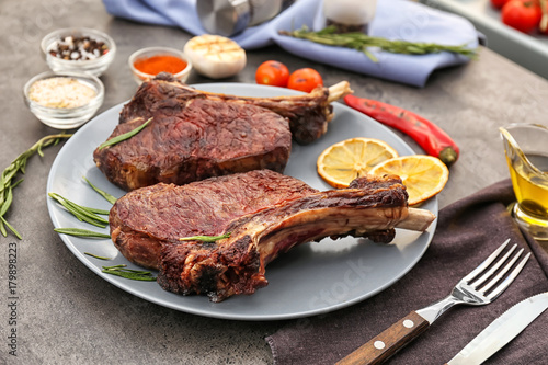 Plate with yummy grilled steaks on kitchen table