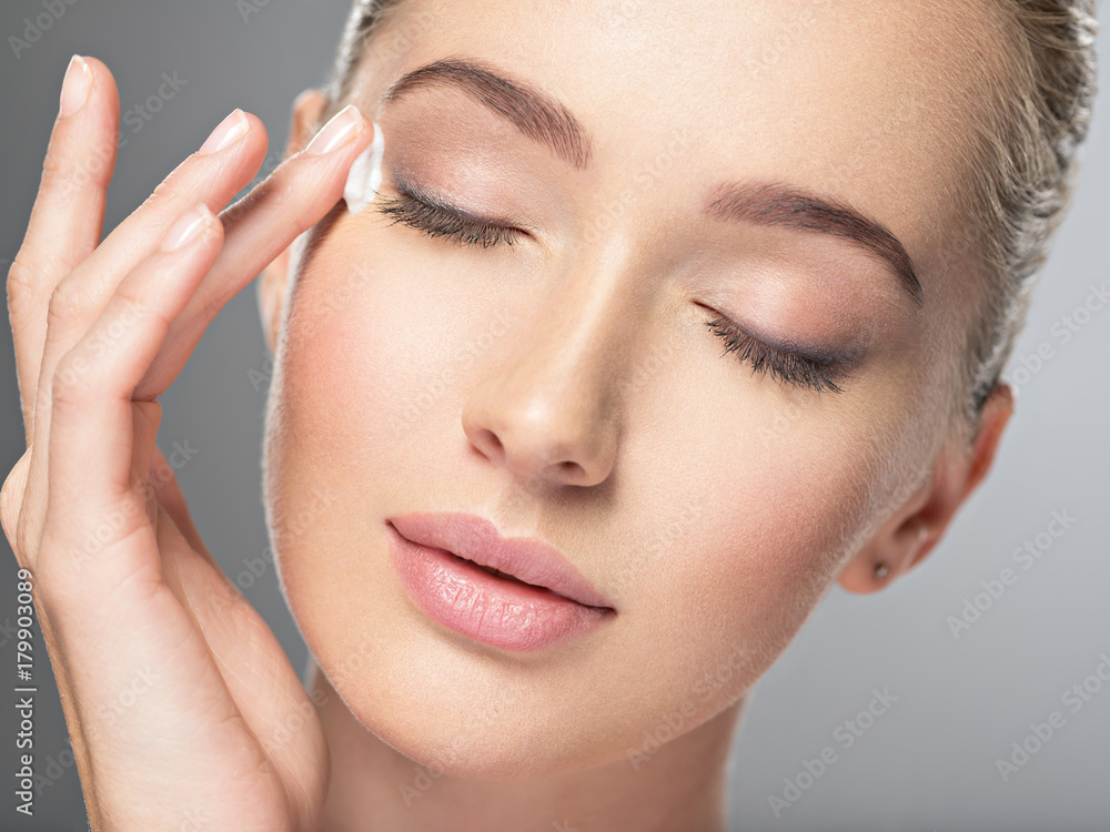 Beautiful young woman gets cream near eyes Beautiful young woman gets cream near eyes