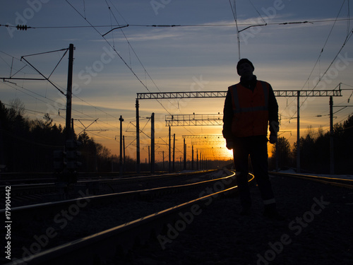 Tableau sur toile lonely railwayman at work during sunset