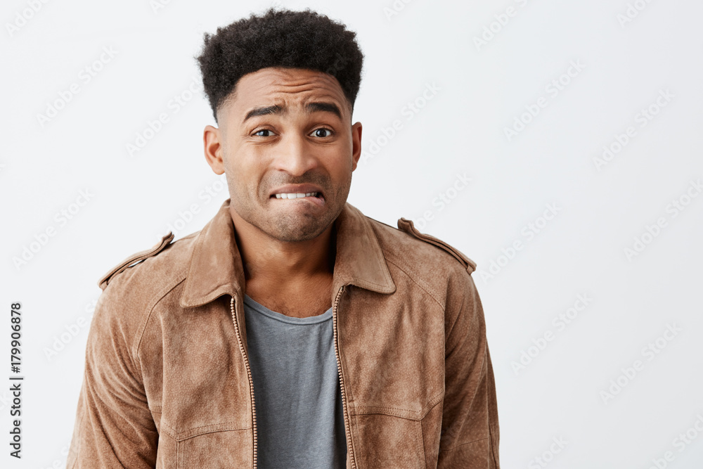 Fototapeta premium Oops. Portrait of unhappy young good-looking afro american men with curly hair in casual stylish clothes looking at mother with guilty face expression after breaking her favorite vase.