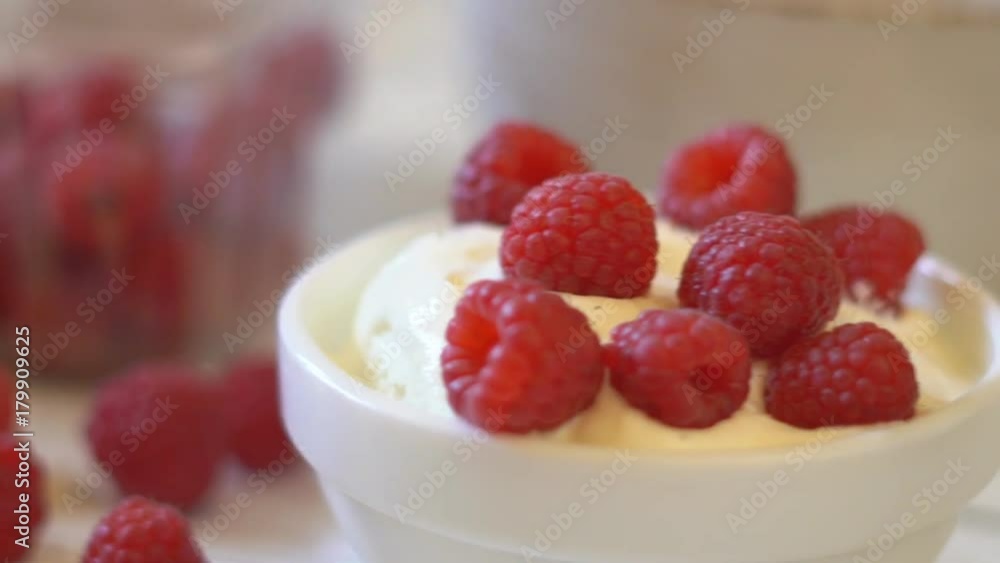 white small bowl with berry yogurt. large ripe berries of raspberries fall from above and lie on a platter. delayed shooting. Juicy and healthy breakfast. tasty and healthy. hd white small bowl with berry yogurt. large ripe berries of raspberries fall from above and lie on a platter. delayed shooting. Juicy and healthy breakfast. tasty and healthy. hd