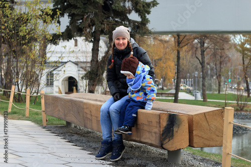 Mother with a child sitting on a bench in autumn Park