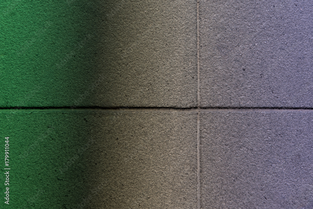 Fototapeta premium Сoncrete tiles illuminated by the transition from green light to violet. Abstract colorful texture background