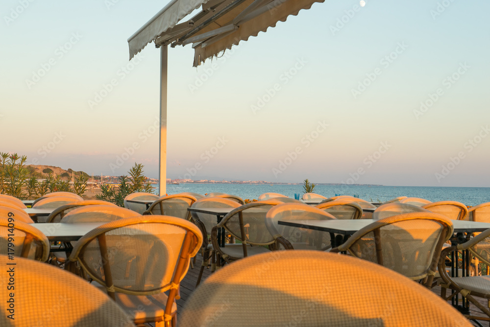 Fototapeta premium chairs and tables on a beach restaurant during sunset