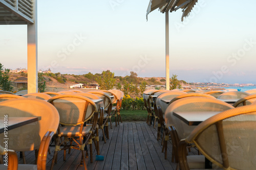 chairs and tables on a beach restaurant during sunset
