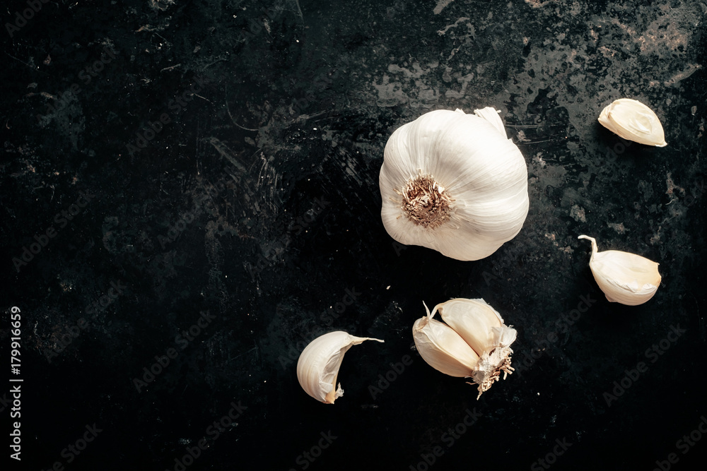 Raw garlic cloves and bulb on antique dark black background. Top view ...