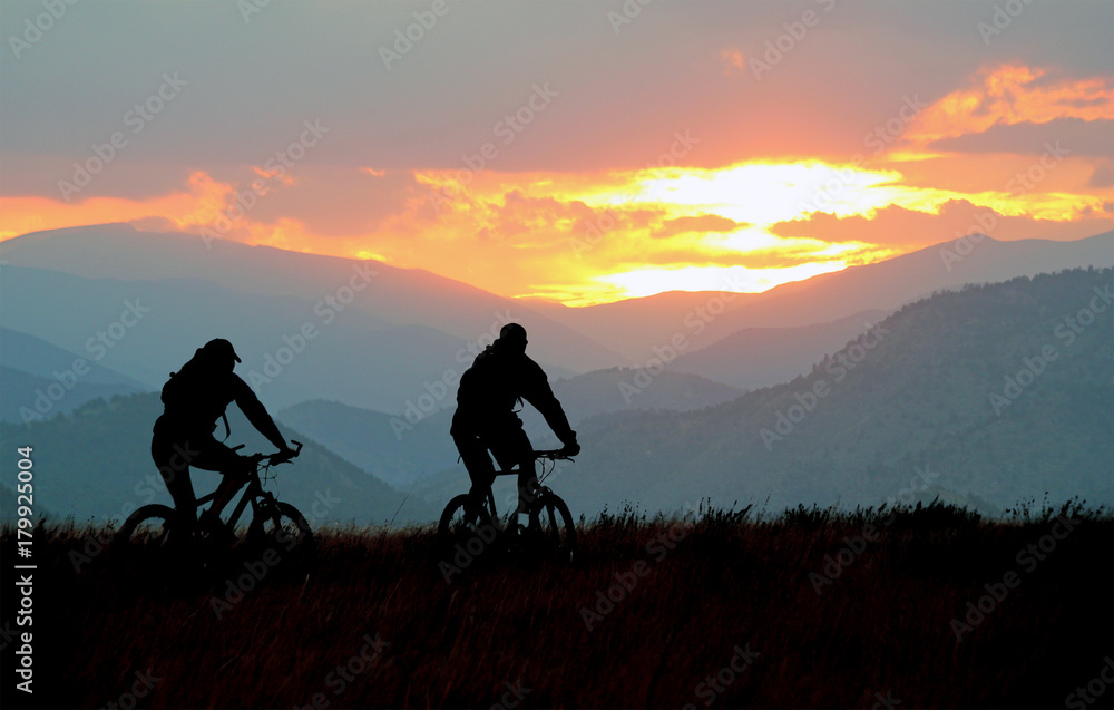 Mountain bikers on a trail at sunset Mountain bikers on a trail at sunset
