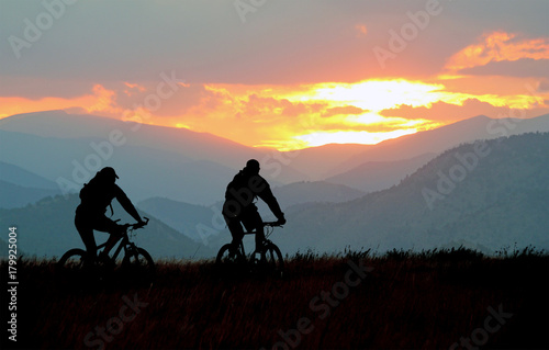 Mountain bikers on a trail at sunset