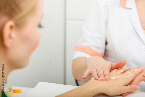 Woman applying cream on hand using spatula