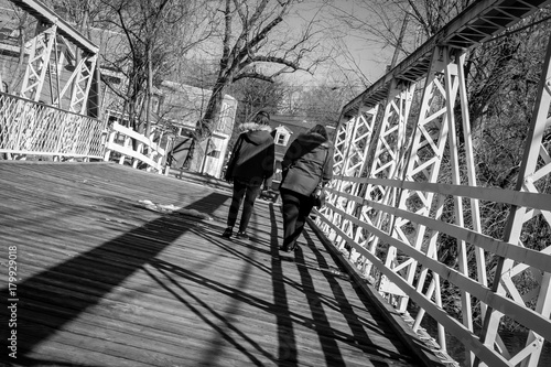Mother and daughter walking on wooden and steel structure bridge. Female friend couple walking on walkway bridge. Light and shadow on industrial architectural bridge. Architecture and industrial art.