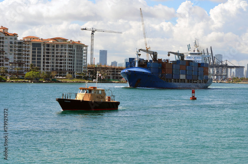 Container ship guided by a pilot boat exiting the Port of Miami via Government Cut.