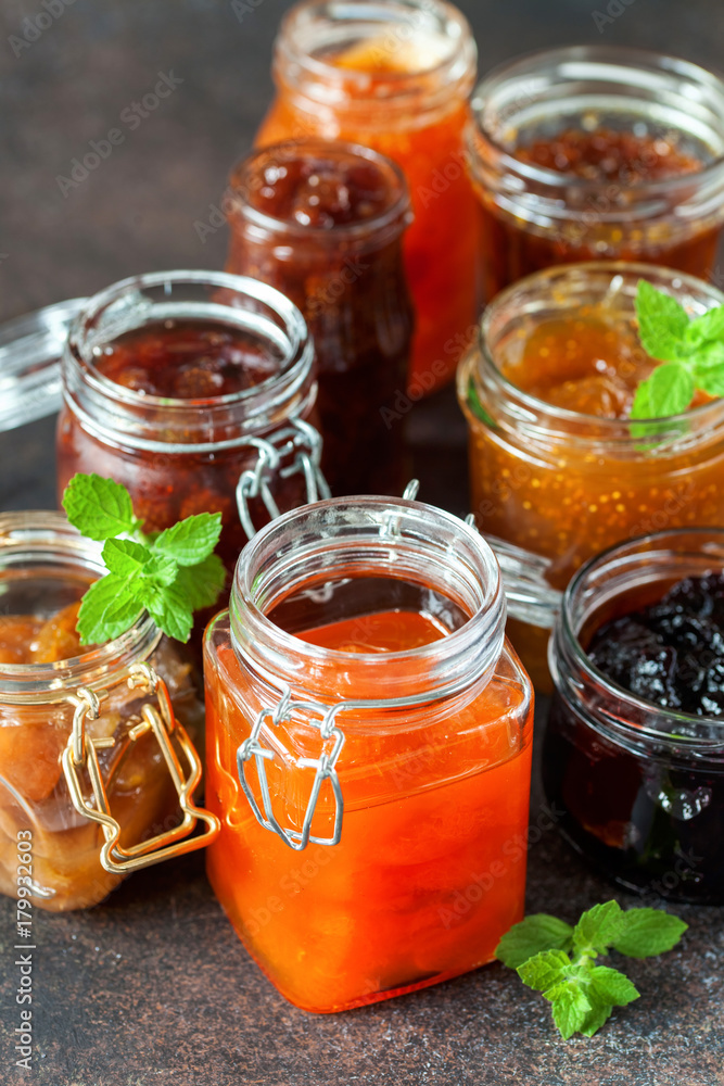 Various jars of fruit jam on dark table. Selective focus Various jars of fruit jam on dark table. Selective focus