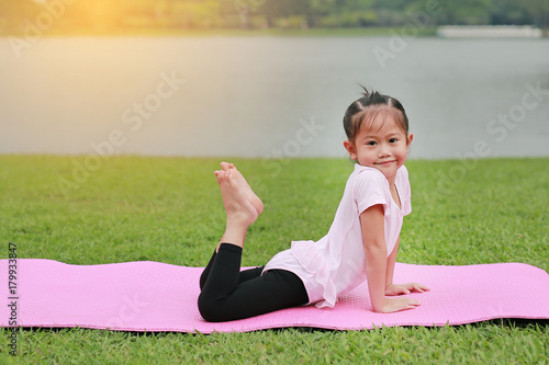 Portrait of little asian child girl doing yoga in the public park.