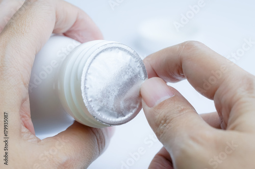 Hands opening foil  protective sealed on top of white plastic bottle for protection pills from broken keep product in good quality.
