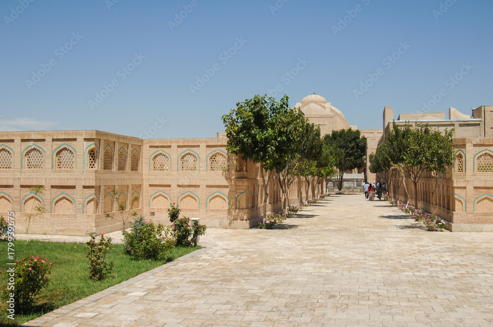 Fototapeta premium Alley with trees and people in the old Eastern city. the ancient buildings of medieval Asia