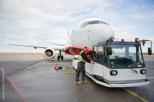 Worker Opening Towing Truck Attached To Airplane