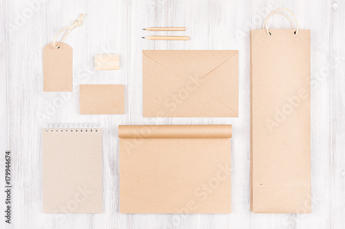 Corporate identity template; packaging, stationery, gift mock up of brown kraft paper on soft white wood background. 