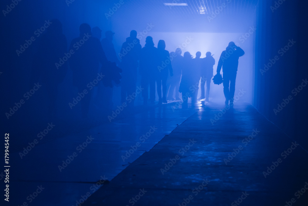 silhouette of people going to work walking in a tunnel in smoke against a background of bright light. mysterious mood