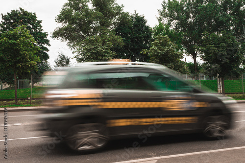 A taxi car at high speed crosses a pedestrian crossing, a motion blur effect.