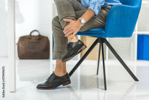 cropped view of tired businesswoman with painful legs sitting in chair © LIGHTFIELD STUDIOS