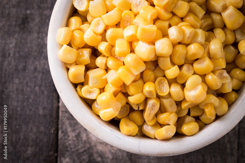 Sweet corn kernels in bowl on wooden table . Cooked canned yellow vegetable, vegetarian staple food. Sweet corn kernels in bowl on wooden table . Cooked canned yellow vegetable, vegetarian staple food.
